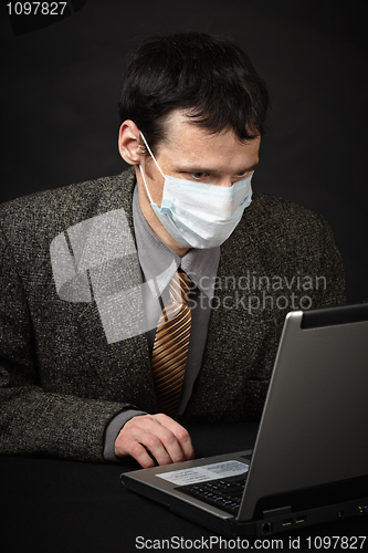 Image of Man in medical mask diagnoses computer