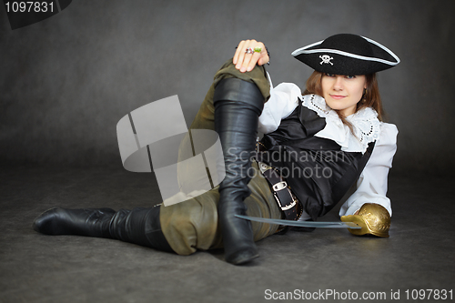 Image of Iimpudent woman pirate lies with sabre on black background