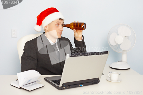 Image of Funny man in New Year's hat looks through a bottle