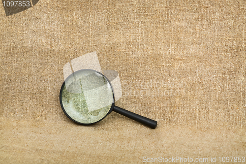 Image of Old magnifier on brown canvas background