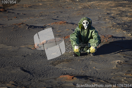 Image of Man in protective clothing sitting in desert