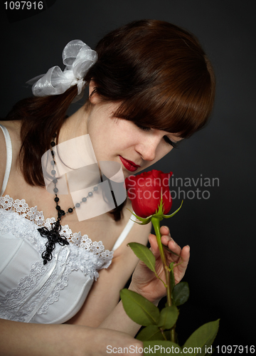 Image of Beautiful girl smells red rose