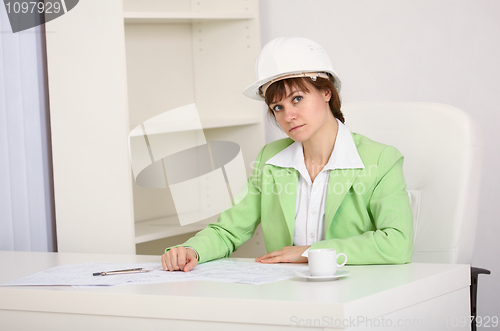 Image of Girl engineer in white helmet on workplace at office