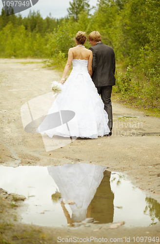 Image of Newly-married couple walks on rural road