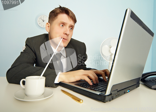 Image of Businessman drinks coffee through a straw and work in Internet