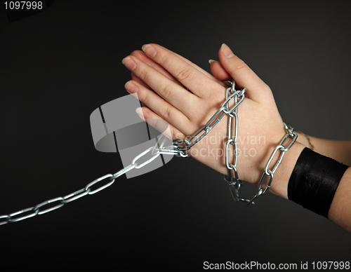 Image of Women's hands shackled a metal chain