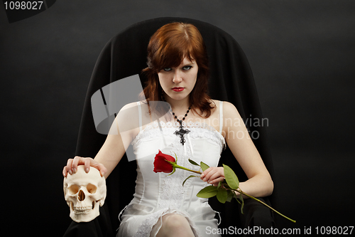 Image of Beautiful girl sitting in chair with skull and rose