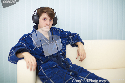 Image of Man in dark blue dressing gown listens to music