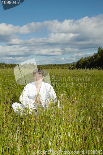 Image of Young man meditates in a field