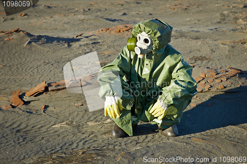 Image of Scientist in protective suit and gas mask sitting on slag
