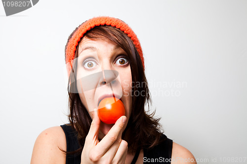 Image of Young woman eating tomato