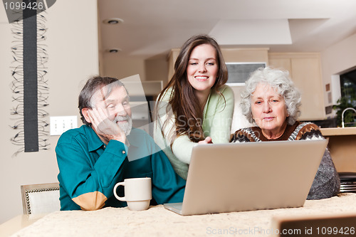 Image of Teenage girl with grandparents using laptop