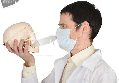 Image of Student medical school in mask looks at skull