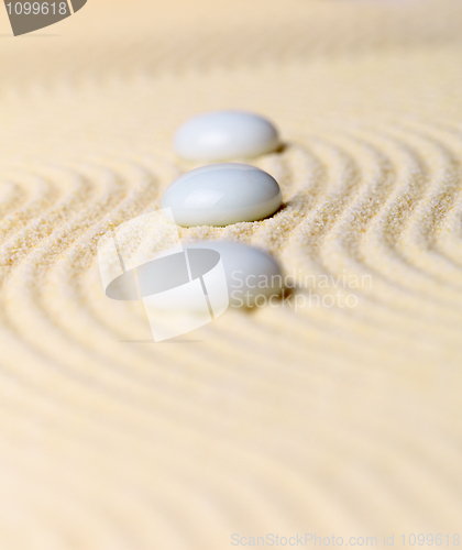 Image of Composition three white stones on yellow sand - Zen Garden