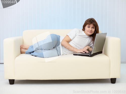 Image of Beautiful young woman with laptop on sofa