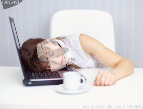 Image of Young woman comically asleep on keyboard at table