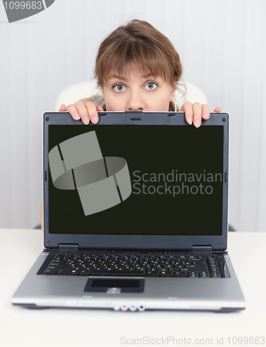 Image of Young girl hiding behind a laptop screen