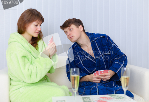 Image of Couple sitting on couch and playing cards