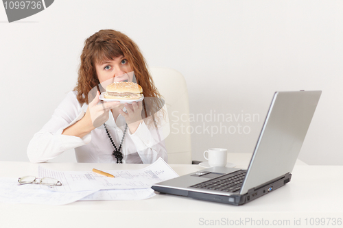 Image of Young woman eagerly have a sandwich