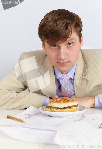Image of Young man in a light jacket and big sandwich