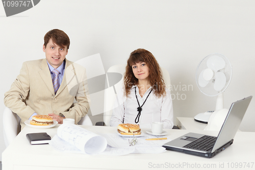 Image of Business people - man and woman meet for dinner at workplace in 