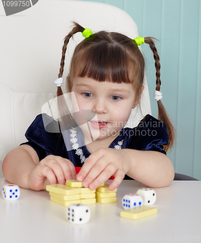 Image of Happy beautiful child plays with toys on table