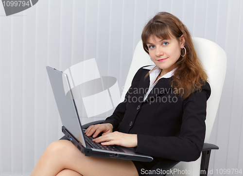 Image of Beautiful young girl sits in office armchair with laptop