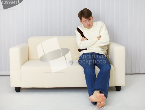 Image of A gloomy man sitting on couch in front of TV