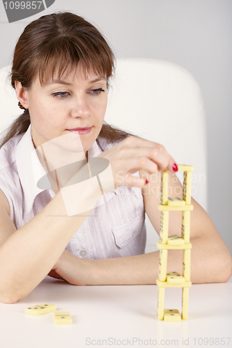 Image of Woman builds precarious tower of dominoes