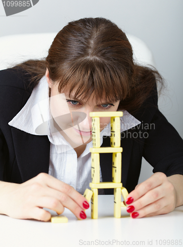 Image of Woman is focused to build a tower with domino on table
