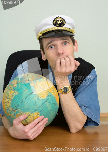 Image of Seaman misses on distant travel sitting at table with globe