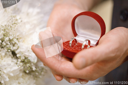 Image of Hands of groom and bride hold casket with rings