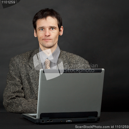 Image of Young man sitting at table with computer