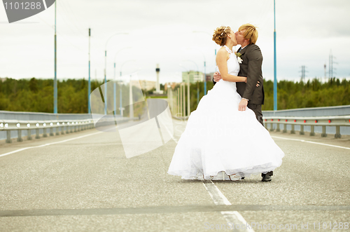 Image of Newlyweds kissing passionately on highway