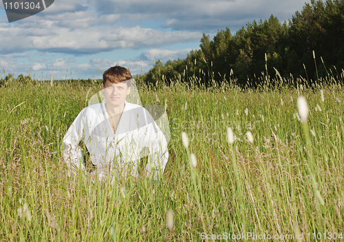 Image of Young man in white kimono sits in grass