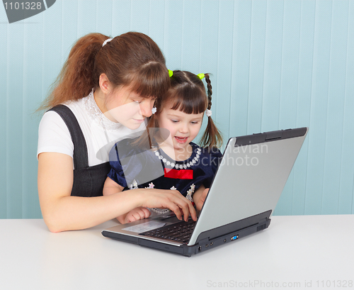 Image of Mother teaches child to use laptop