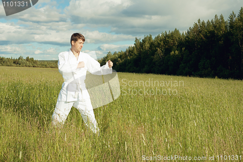 Image of Man in kimono trains karate in open air