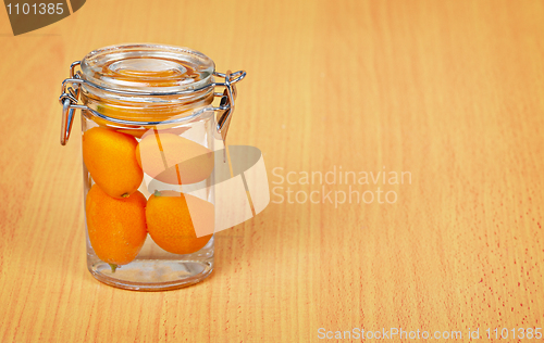 Image of Kumquat inside a glass jar on wooden background