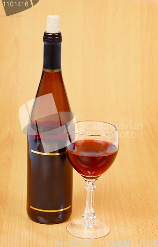 Image of Bottle of red wine and glass on wooden table