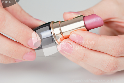 Image of Hands hold lipstick - a close up