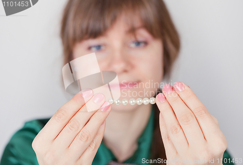 Image of Young girl admires a beads from pearls