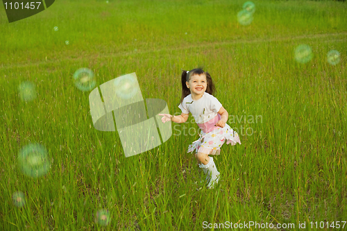 Image of Happy little girl among soap bubbles