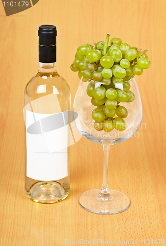 Image of A bottle of wine, a large glass and grapes