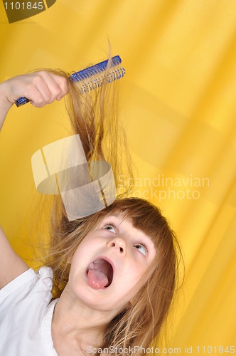 Image of child having problem with brushing her hair