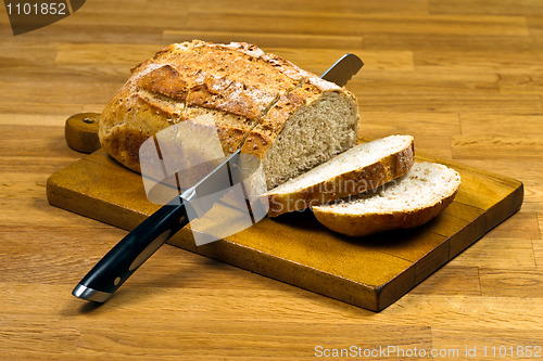 Image of Wooden cutting board with white bread and knife