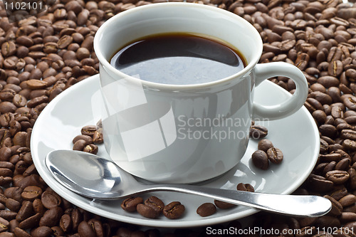 Image of Coffee beans in white cup on saucer with spoon