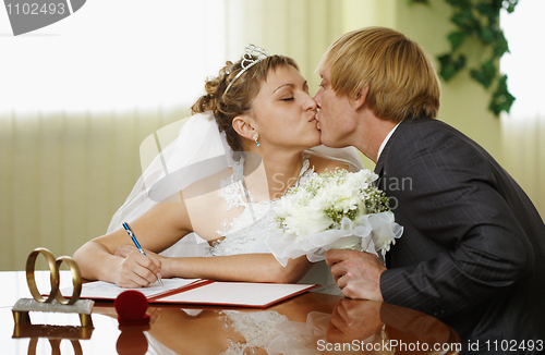 Image of Bride and groom kiss during ceremony of marriage