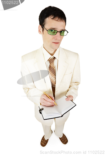 Image of Young businessman in light suit writes in notebook