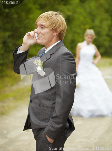 Image of Groom has turned away from bride and speaks on phone