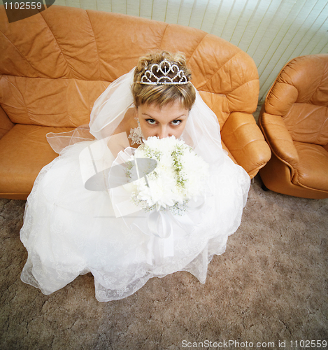 Image of Bride sits on leathern sofa